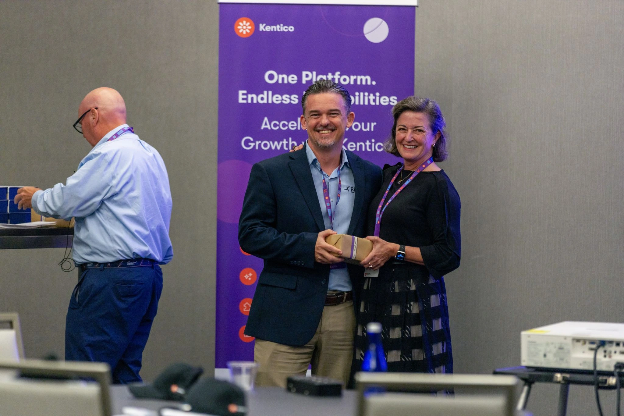 kentico-event-gift-digital-experience-platform.webp Two people smiling while receiving a gift at a Kentico event promoting digital experience platforms.